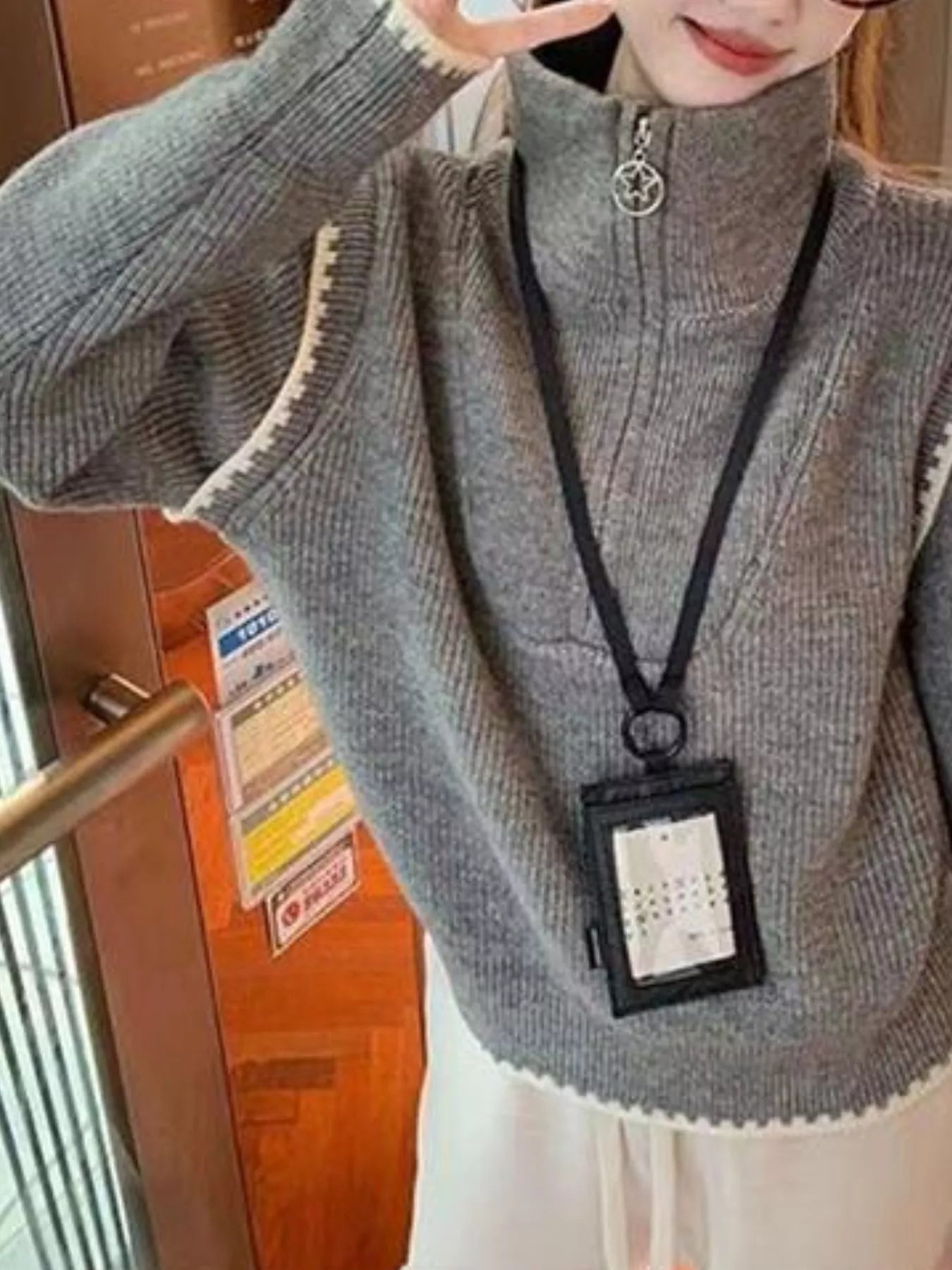 Gray knit pullover sweater with half-zip collar and star zipper charm detailing.