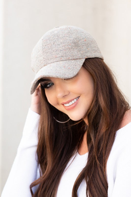 Beige tweed baseball cap with curved brim and textured wool-blend fabric.