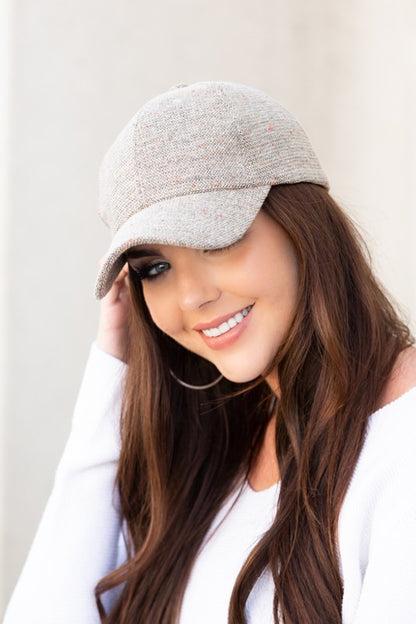 Beige tweed baseball cap with curved brim and textured wool-blend fabric.