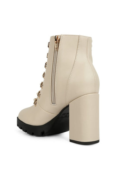 Ivory ankle boot with chunky heel, side zipper, and gold hardware detailing, made of faux leather.
