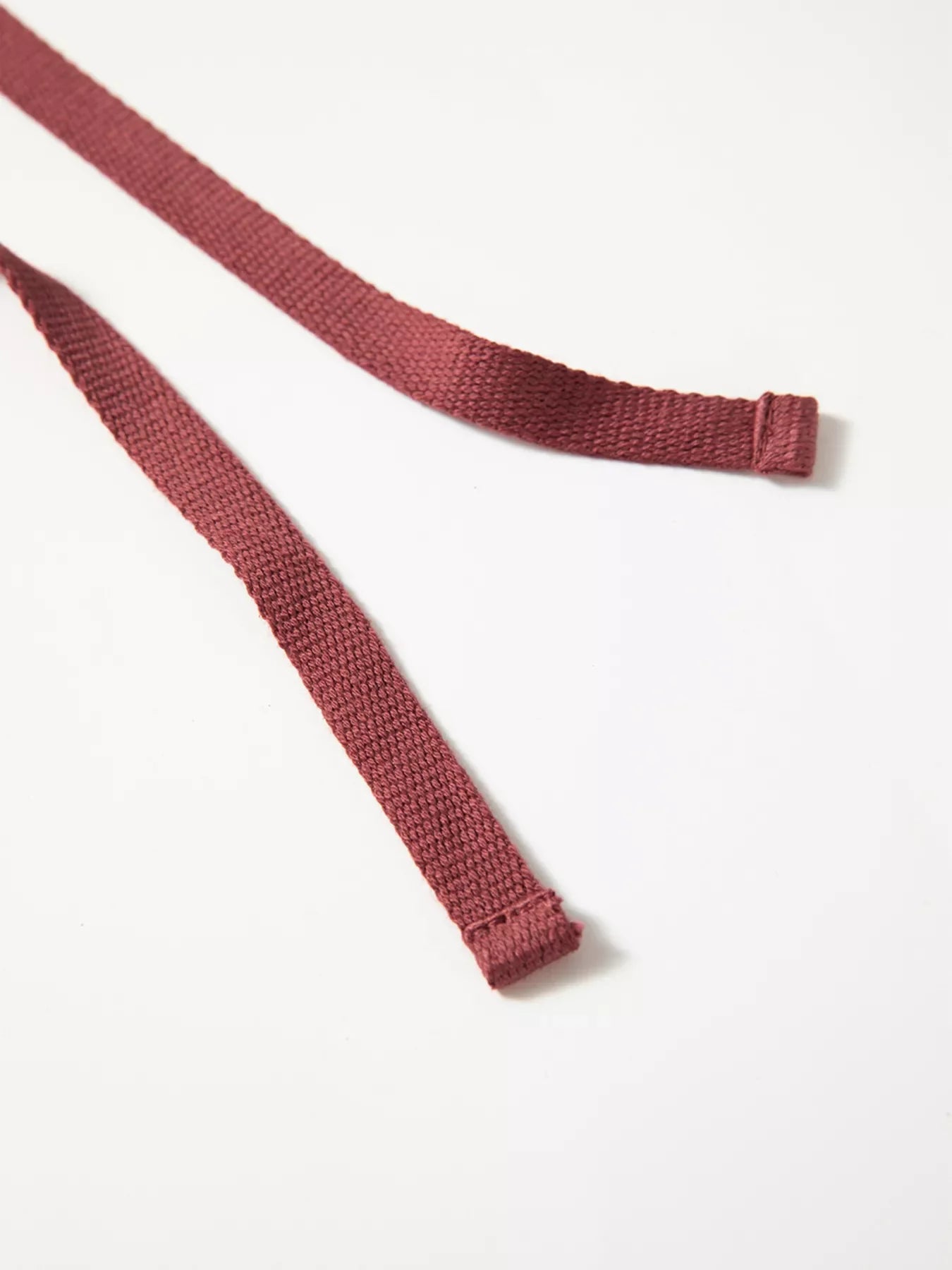 Maroon cotton drawstring ties with stitched ends, made from durable woven fabric.