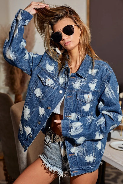 Blue distressed denim jacket with bleached patches and button-up front.