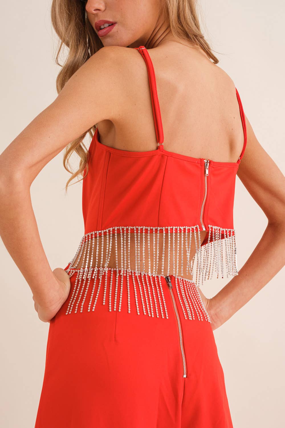 Red fringe jumpsuit with spaghetti straps and mesh waist detail with rhinestone embellishments.