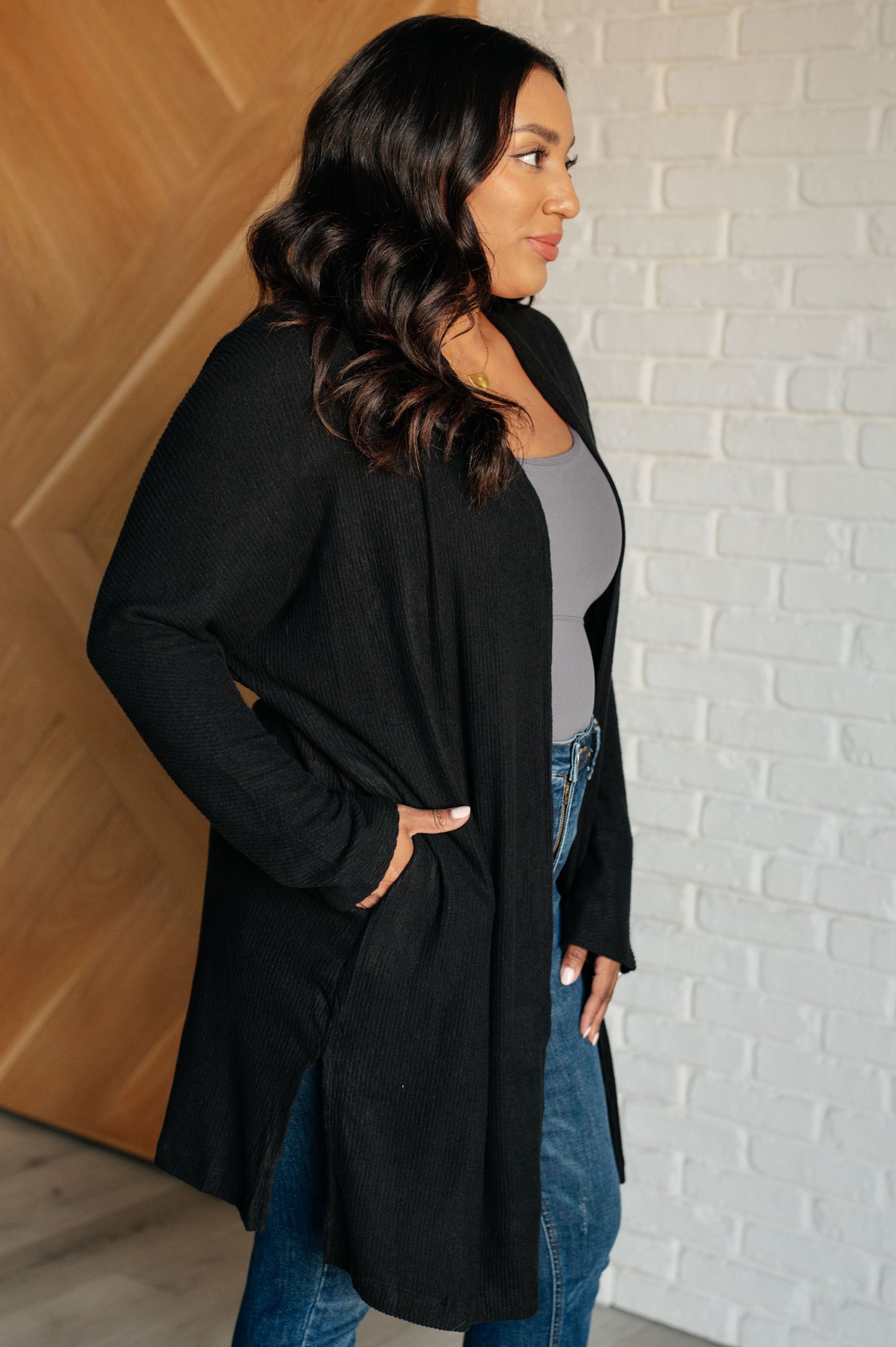 Black ribbed knit cardigan with open front and side slits for added comfort and layering.