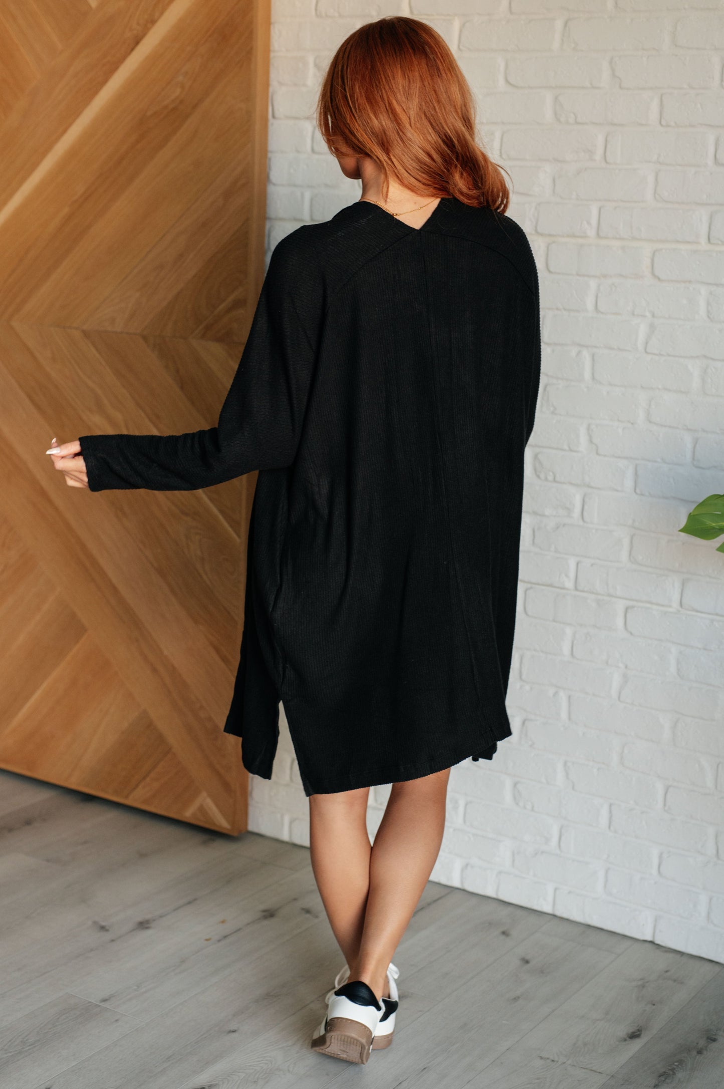 Black knit cardigan dress with long sleeves and soft ribbed fabric.