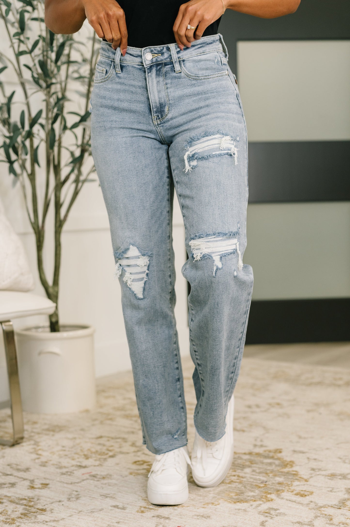 Light wash blue distressed jeans with high-rise waist and ripped denim detailing.