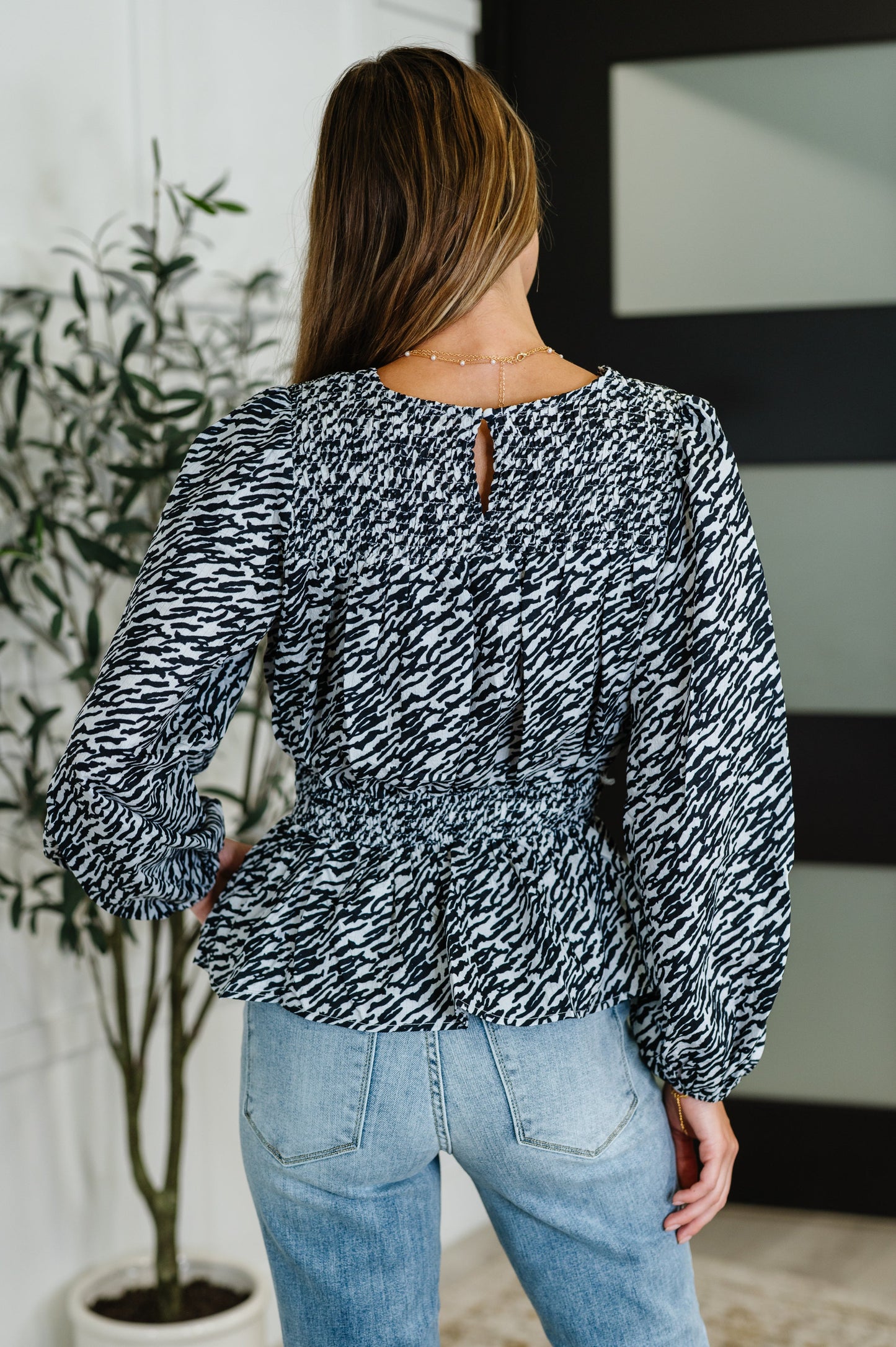 Zebra Print Peplum Top in black and white with long sleeves and smocked waist detail.
