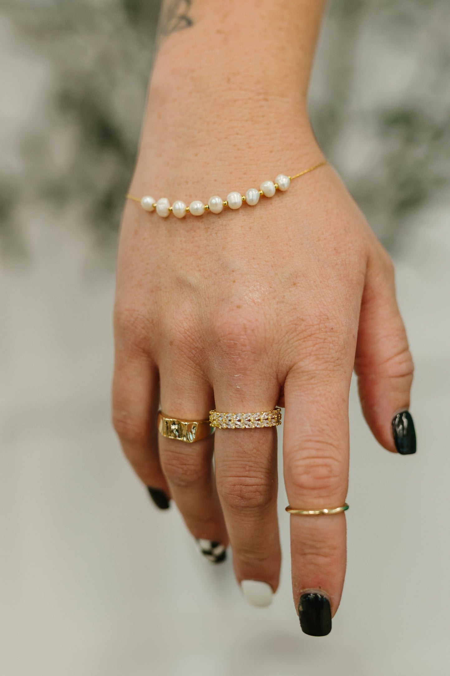 Hand wearing multiple gold rings with a blurred background