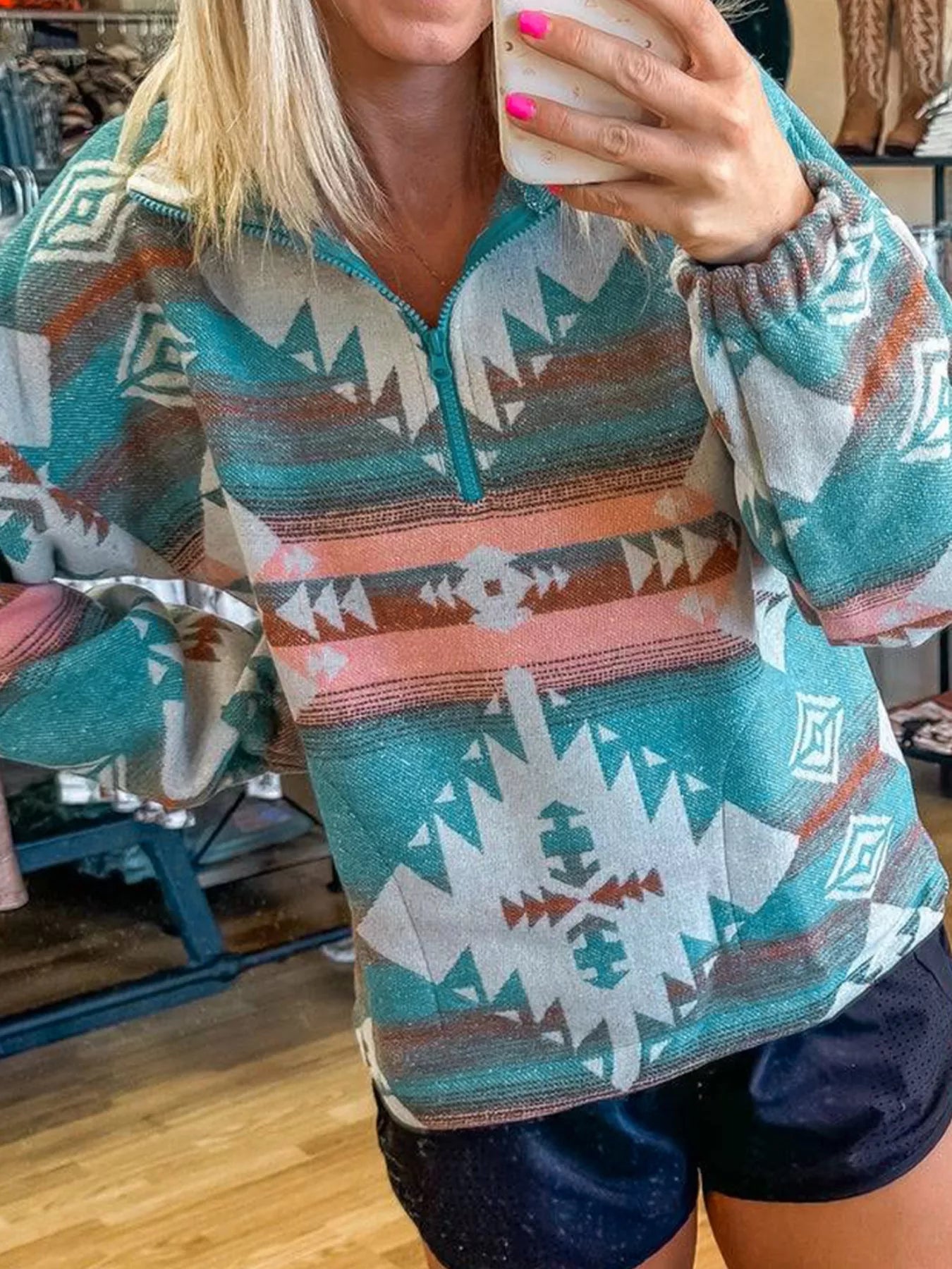 Teal and coral Aztec-print pullover with half-zip front and soft fleece material.