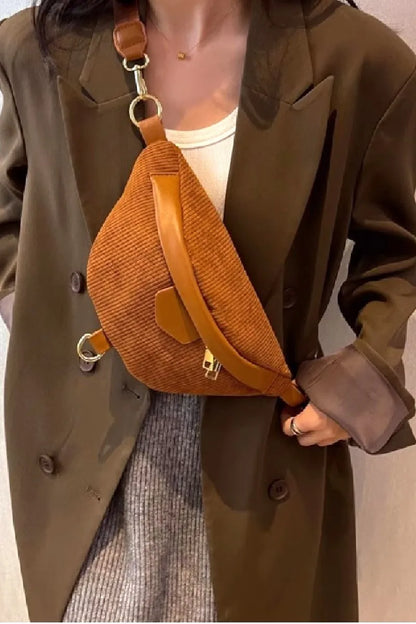Rust brown crossbody bag with leather strap and corduroy fabric.