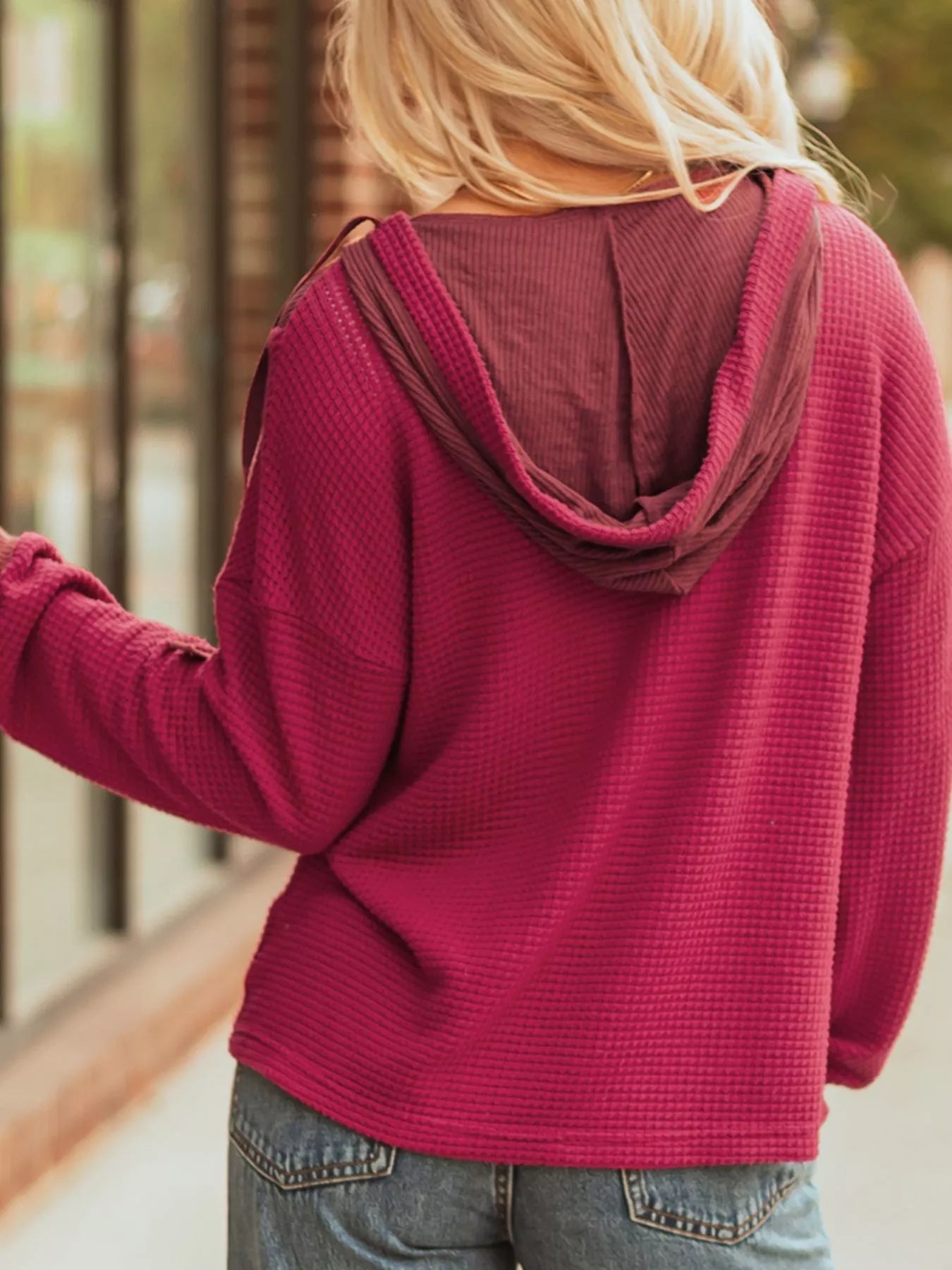 Magenta waffle knit hoodie with contrast hood and relaxed fit.