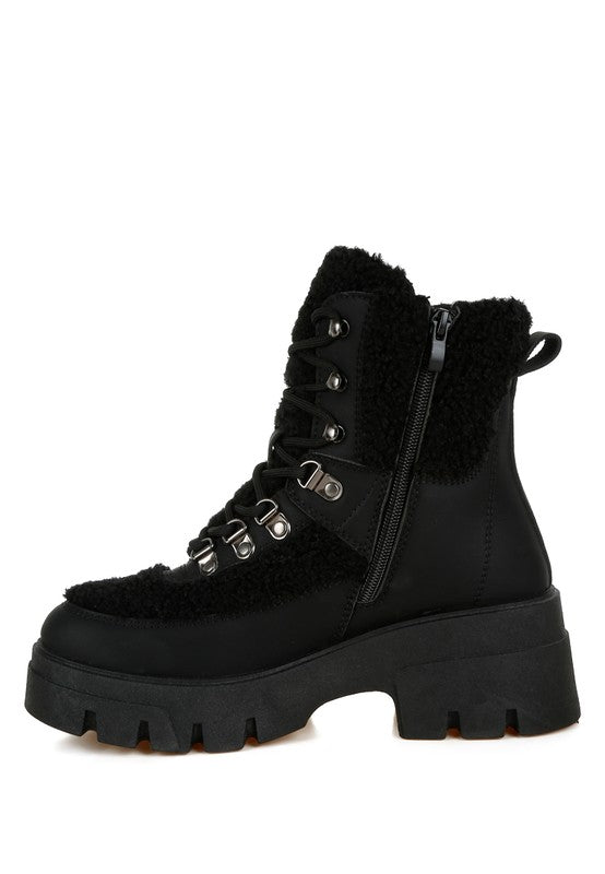 Black combat boot with faux shearling trim and chunky lug sole.
